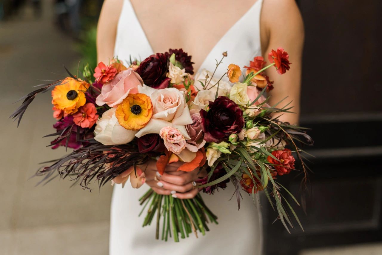Bride with her deep red, orange and pink bridal bouquet. 