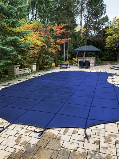 Covered swimming pool in a backyard with autumn trees.