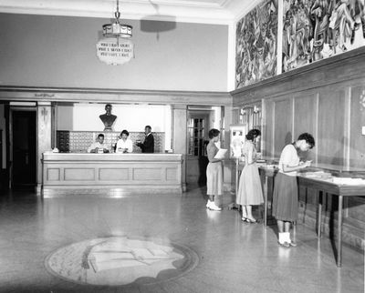 Vintage photograph of students in the lobby of Savery Library; the Amistad murals can be seen above.