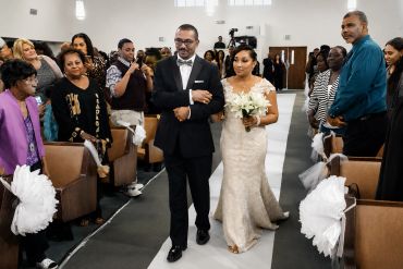 Bride walking down the aisle with man at wedding.