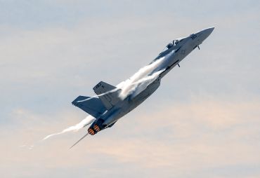 Fighter jet climbing rapidly with afterburners on.