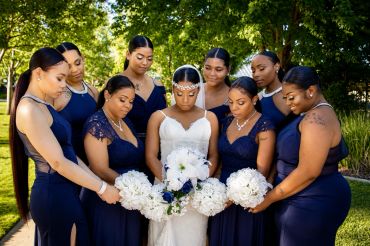 Bride and bridesmaids holding white bouquets outdoors.