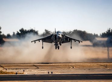 Military jet fighter taking off from runway.