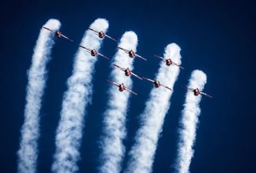 Nine planes flying in formation with smoke trails.