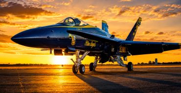 Blue Angels fighter jet on runway at sunset.