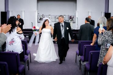 Newlyweds walk down the aisle happily holding hands.