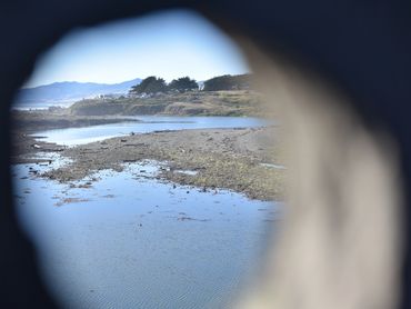 View of a river and shoreline through a circular opening in a structure.