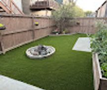 Small backyard with artificial grass and fire pit.
