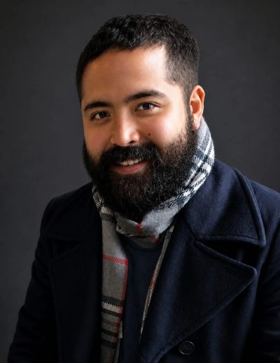 Hombre sonriente con chaqueta y bufanda.