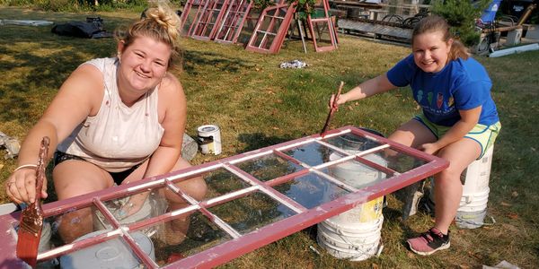 Two student workers painting window pane red