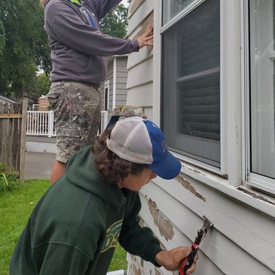 two Prairie Rose studnet painters scraping siding before an exterior painting project