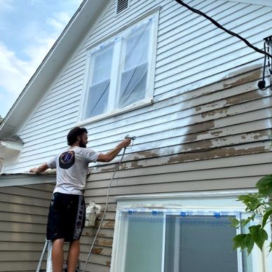 Student worker spray painting outside of home