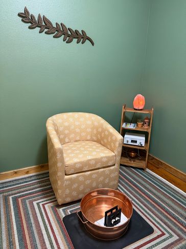 Cozy room corner with a patterned chair and salt lamp.
