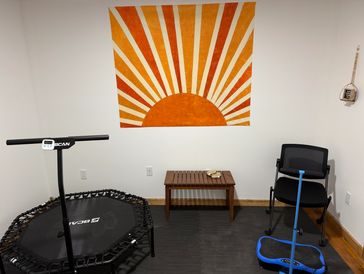 Room with exercise equipment and sun-themed wall art.