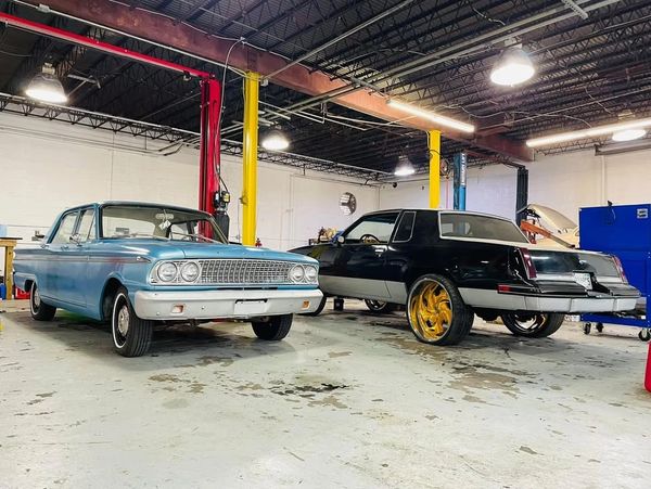 Two classic cars parked inside a spacious garage with bright lighting.