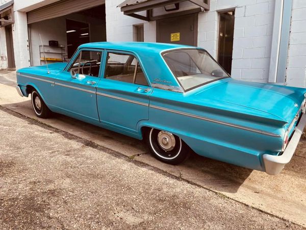 A vintage turquoise Ford Galaxie parked beside a building.