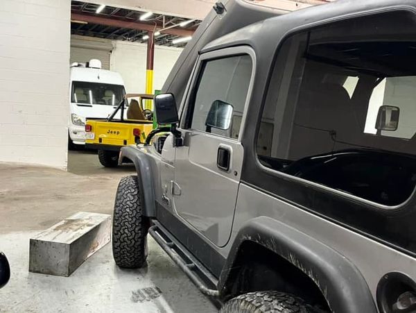 Two Jeep vehicles parked inside a garage with industrial lighting.