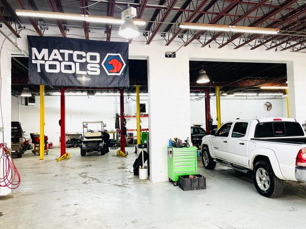 Car repair shop with white truck and Matco Tools banner.