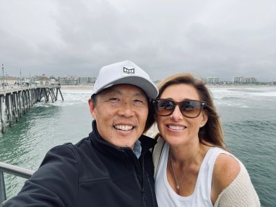 Smiling couple takes a selfie by the beach on a cloudy day.