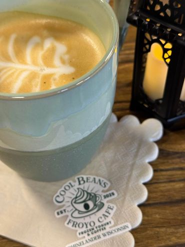 Latte with foam art in a pastel blue cup at Cool Beans Froyo Cafe.