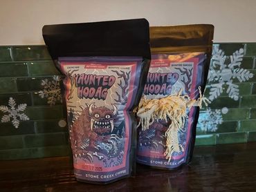 Two bags of Haunted Hodag coffee on a wooden surface with snowflake decorations in the background.