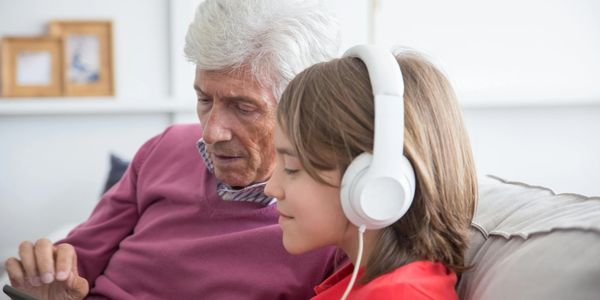Male grandparent with older boy wearing headphones