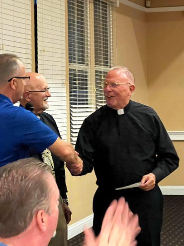 President Vince Ferrante and Boardmember Peter Cardinale present a club donation to Fr. Roberts.