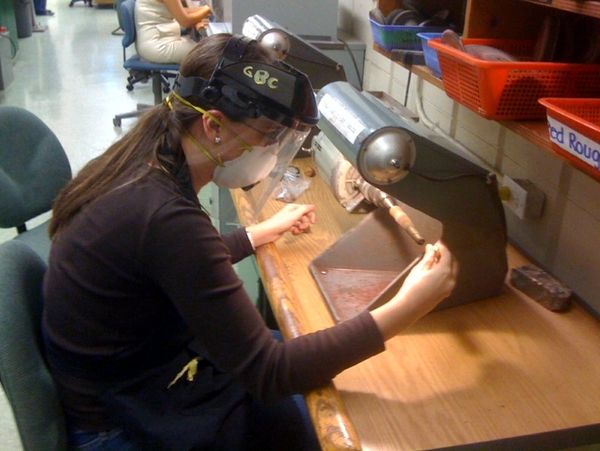 Lady working on a polish machine for jewelry. 