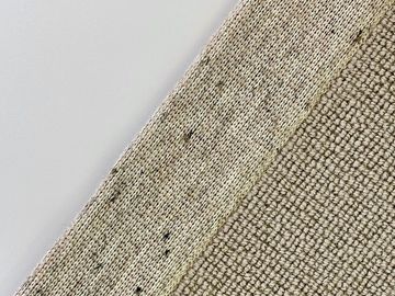Close-up of textured beige fabric with subtle variations and small dark specks.