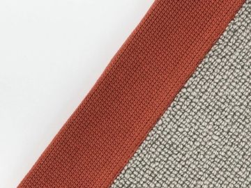 Close-up of two textured fabric pieces in rust red and gray tones.
