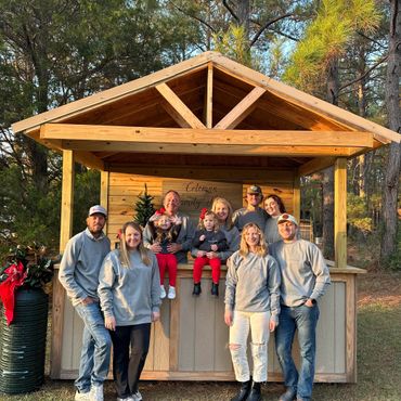 Family gathered in front of a wooden cabin, smiling and enjoying a sunny day.