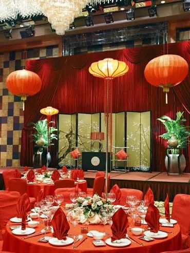 Elegant banquet hall decorated with red lanterns and table settings for a festive event.