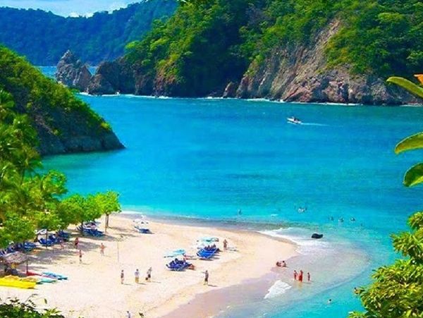 Scenic tropical beach with turquoise waters and lush green hills.