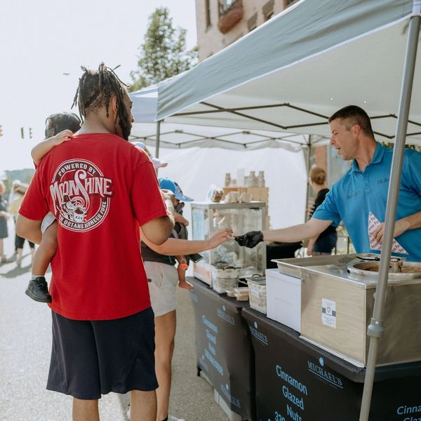 Michael’s Confections serving candied nut samples to a customer