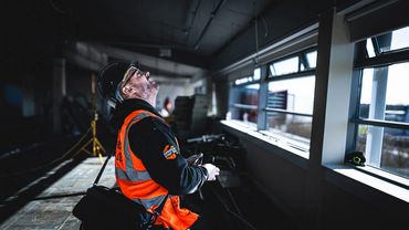 Construction worker inspecting ceiling inside a building under renovation.