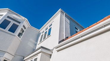 Bright blue sky above a white modern house with clean windows.
