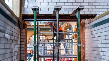 Construction worker on scaffolding inside a building under renovation.