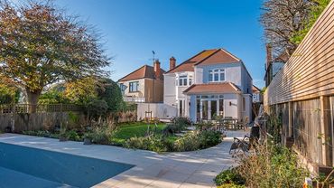 Modern house with backyard garden and empty pool on a sunny day.