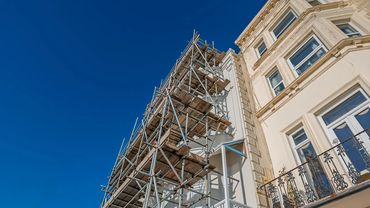 Metal scaffolding erected against a building under clear blue sky.