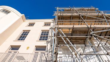Scaffolding set up against a white building under a clear blue sky.