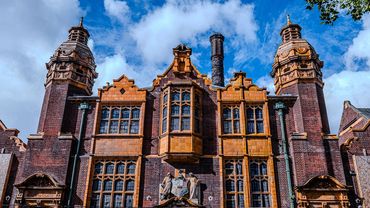 Historic brick building with ornate yellow accents and towers under a blue sky.