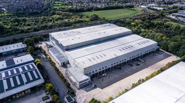 A large industrial warehouse complex surrounded by greenery and roads.