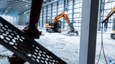 Industrial excavator working inside a large warehouse under construction.