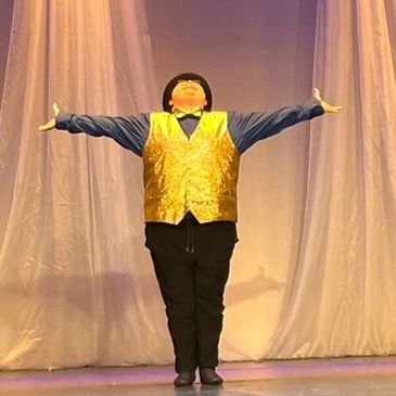 Photo of dance student with arms spread getting ready to take bow after dance.