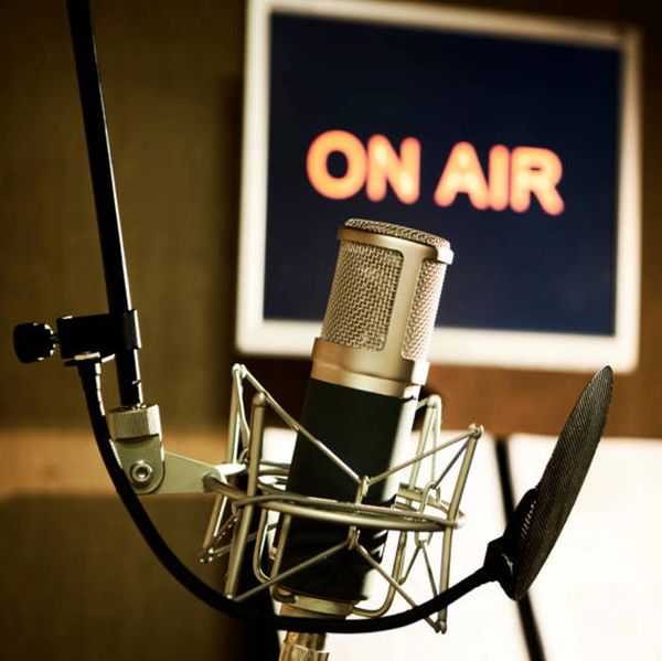 A studio microphone with an 'ON AIR' sign in the background.