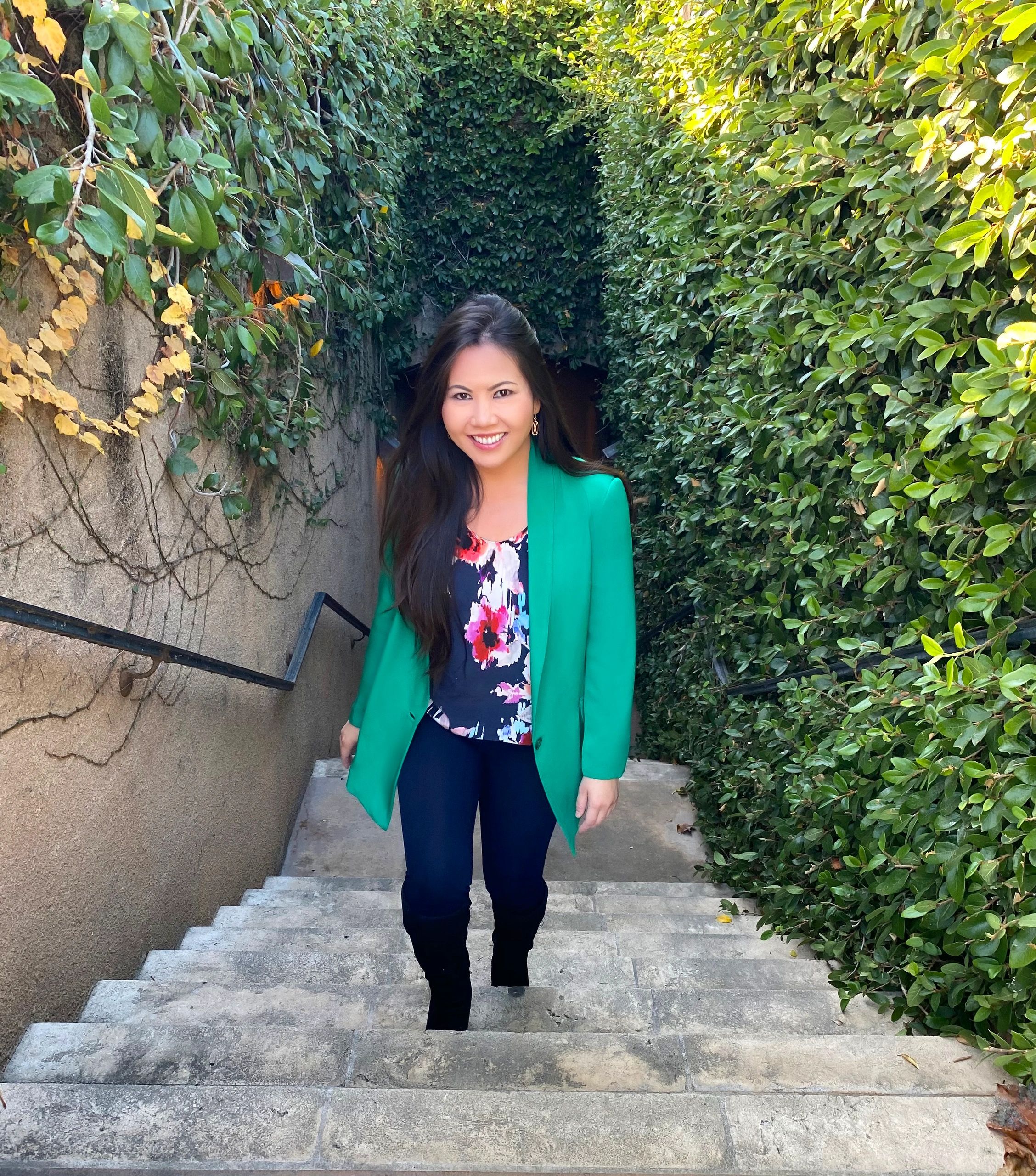 A woman smiling while walking up stairs surrounded by greenery.