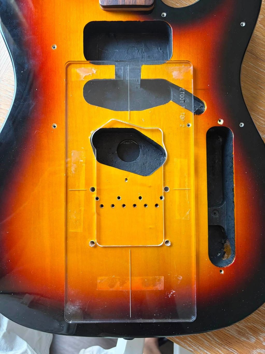 Close-up of a sunburst electric guitar body with a plastic template.