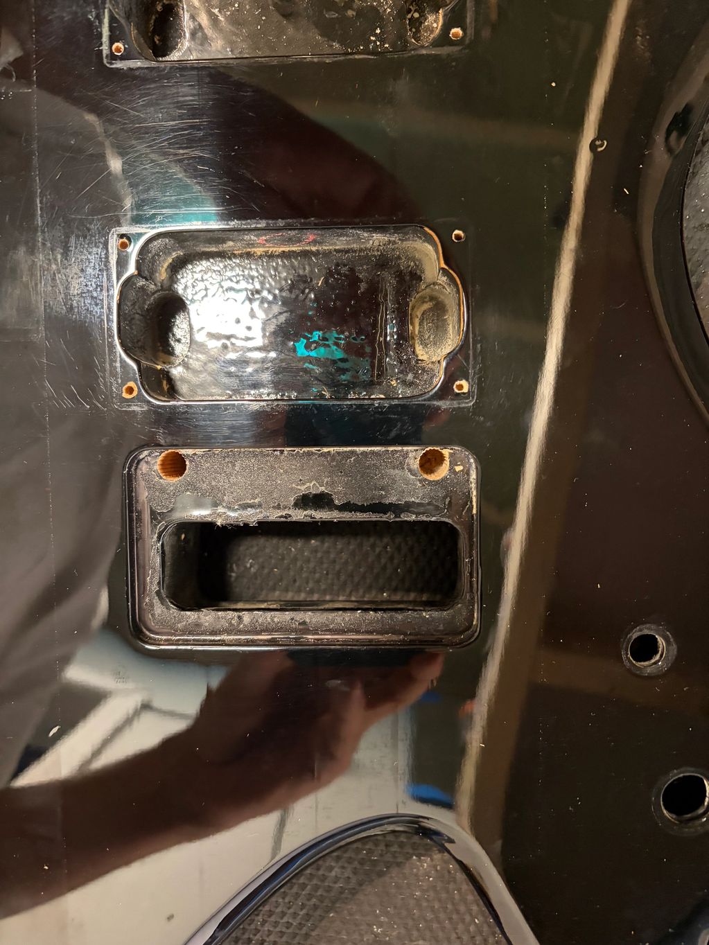 Close-up of a black guitar body with pickup cavities.