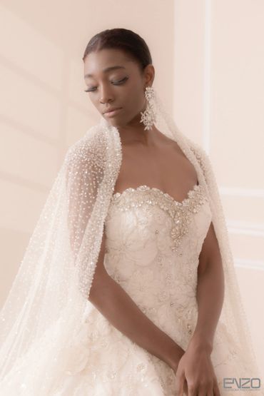 Elegant bride in a detailed, beaded wedding gown with matching earrings.
