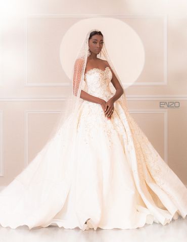 Elegant bride in a detailed white gown and veil poses gracefully.